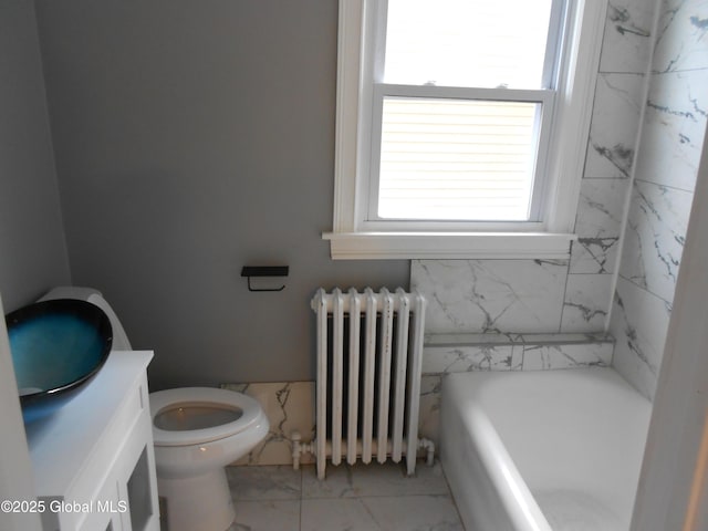 bathroom featuring a bath, radiator heating unit, vanity, and toilet