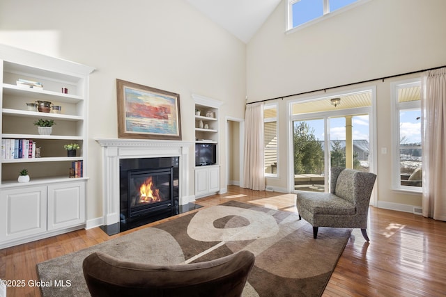 living room featuring light hardwood / wood-style flooring, a high ceiling, and built in shelves