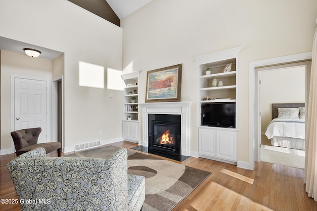 living room with light wood-type flooring, lofted ceiling, and built in shelves