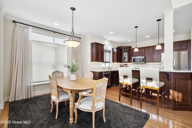 dining area featuring crown molding, light hardwood / wood-style flooring, and sink