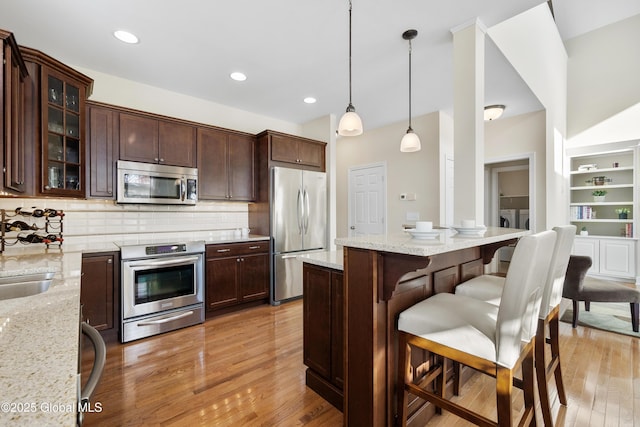 kitchen featuring light stone countertops, dark brown cabinetry, appliances with stainless steel finishes, and washing machine and dryer