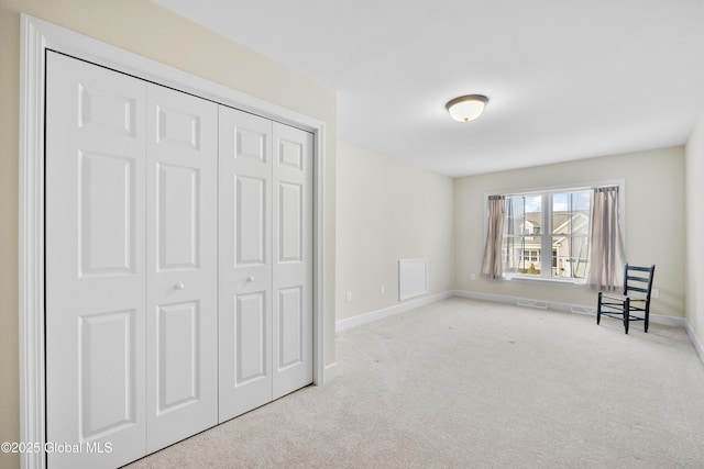 unfurnished bedroom with light colored carpet and a closet