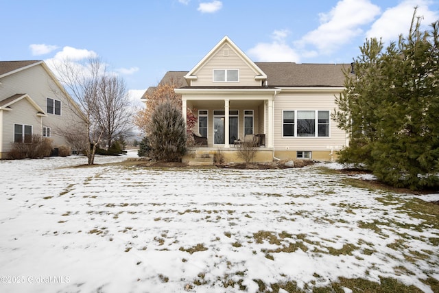 snow covered rear of property featuring a porch