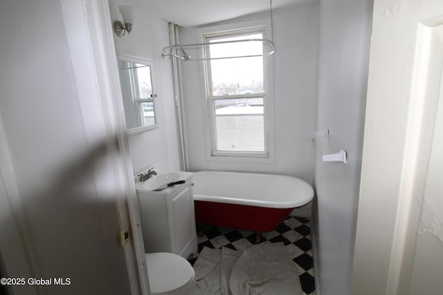 bathroom featuring a tub to relax in, vanity, and toilet