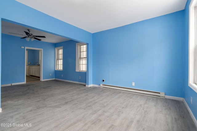 spare room with ceiling fan, light wood-type flooring, and a baseboard radiator