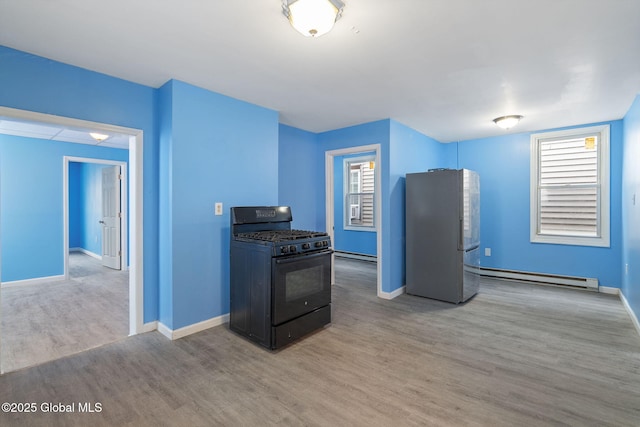 kitchen featuring black gas range, light hardwood / wood-style floors, a baseboard heating unit, and stainless steel refrigerator