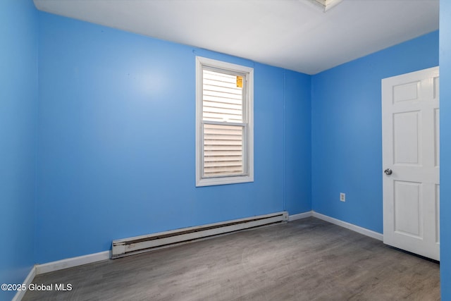 spare room featuring baseboard heating and hardwood / wood-style floors