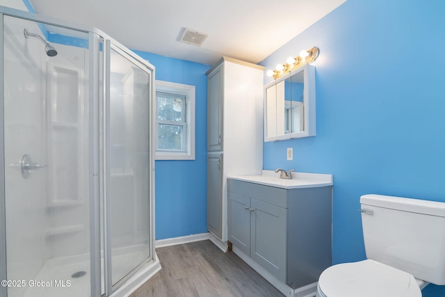 bathroom with a shower with shower door, wood-type flooring, toilet, and vanity