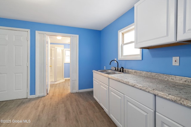 kitchen featuring light wood-type flooring, sink, and white cabinetry