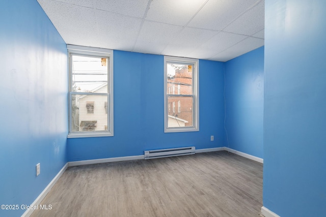 spare room featuring a paneled ceiling, light hardwood / wood-style floors, and a baseboard heating unit