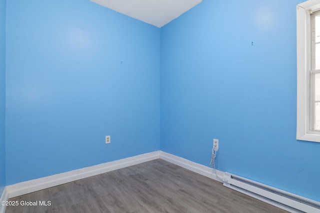 empty room with a baseboard heating unit and hardwood / wood-style flooring