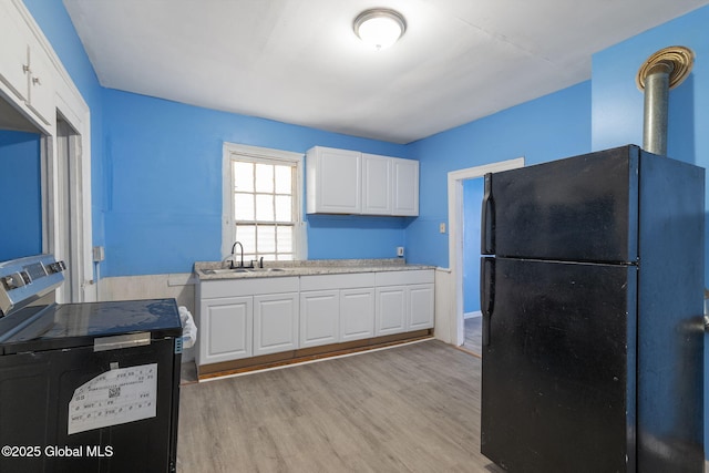 kitchen featuring stainless steel range with electric stovetop, sink, white cabinetry, and black fridge