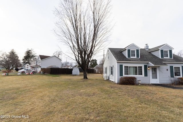 view of side of property featuring a storage unit and a lawn