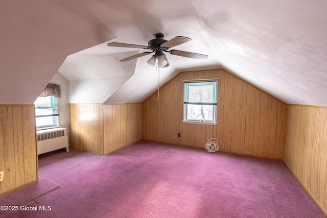 bonus room with a healthy amount of sunlight, ceiling fan, wooden walls, and radiator