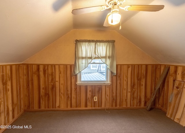 bonus room with lofted ceiling, wood walls, ceiling fan, and carpet