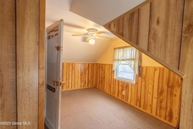 bonus room with lofted ceiling, carpet floors, ceiling fan, and wooden walls