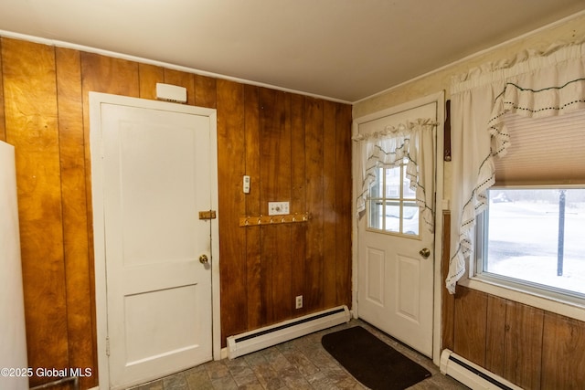 doorway with baseboard heating and wood walls