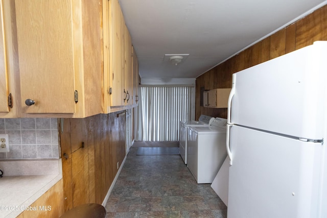 kitchen featuring independent washer and dryer, white refrigerator, and wooden walls