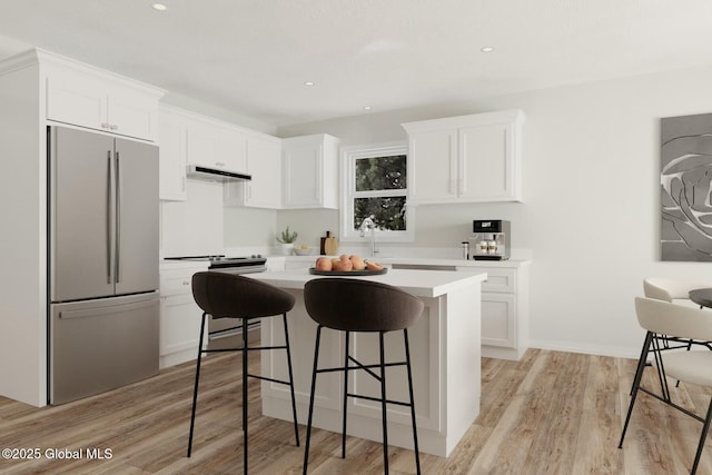 kitchen featuring a breakfast bar area, light wood-type flooring, stainless steel fridge, a kitchen island, and white cabinetry