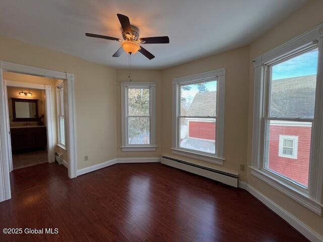 unfurnished room with ceiling fan, dark hardwood / wood-style flooring, and a baseboard radiator