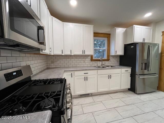 kitchen featuring sink, white cabinets, backsplash, and appliances with stainless steel finishes