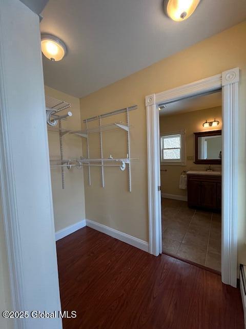 spacious closet with sink, baseboard heating, and dark hardwood / wood-style floors