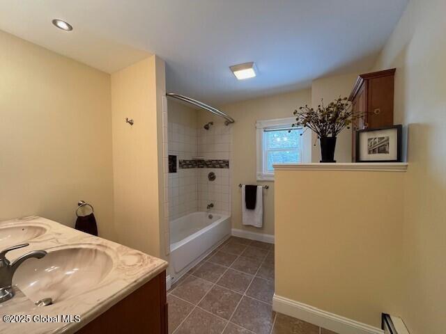 bathroom featuring a baseboard heating unit, tile patterned flooring, vanity, and tiled shower / bath