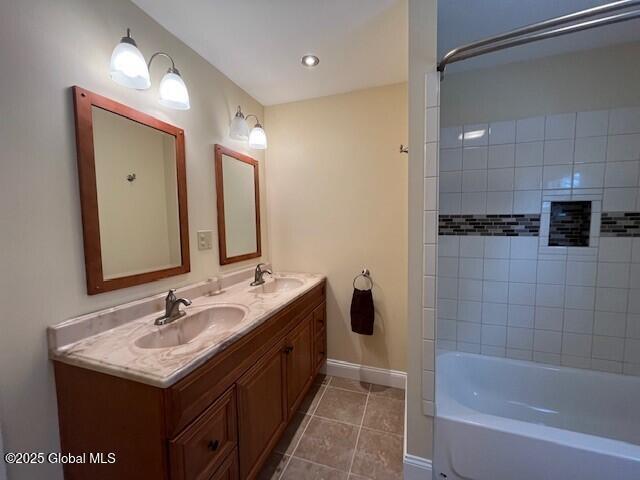 bathroom with tiled shower / bath combo, tile patterned flooring, and vanity