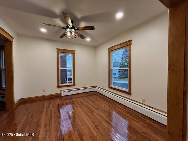 spare room featuring ceiling fan, a baseboard radiator, and wood-type flooring