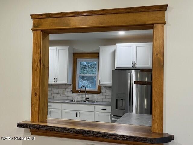 kitchen with sink, stainless steel fridge with ice dispenser, white cabinetry, and tasteful backsplash