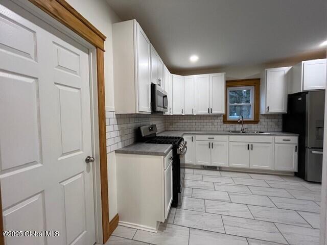 kitchen with sink, stainless steel appliances, white cabinetry, and tasteful backsplash