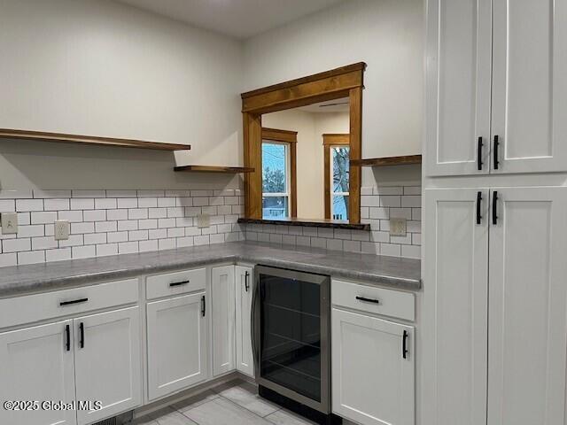 kitchen with beverage cooler, light tile patterned floors, tasteful backsplash, and white cabinetry