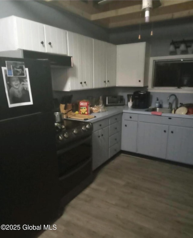 kitchen with sink, white cabinetry, hardwood / wood-style floors, and black appliances