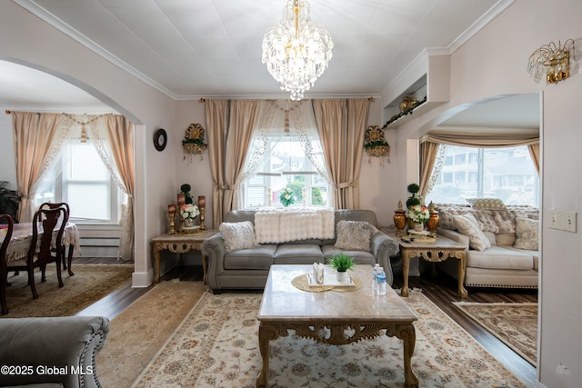 living room featuring hardwood / wood-style floors, a baseboard heating unit, crown molding, and an inviting chandelier