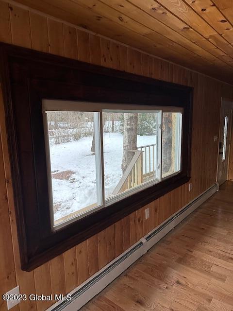 room details featuring baseboard heating, wooden ceiling, wooden walls, and hardwood / wood-style flooring