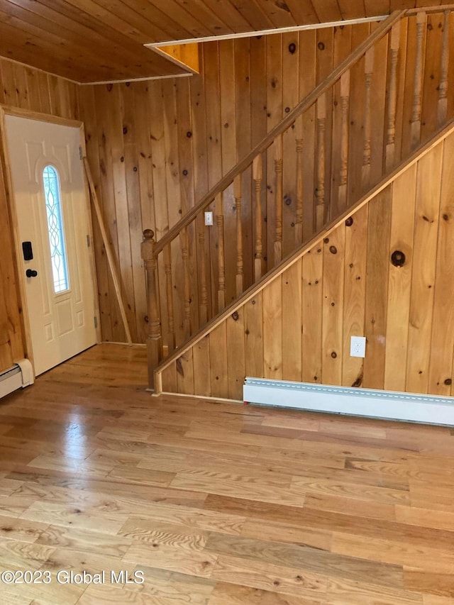 entryway featuring light wood-type flooring, wooden walls, a baseboard radiator, and wood ceiling