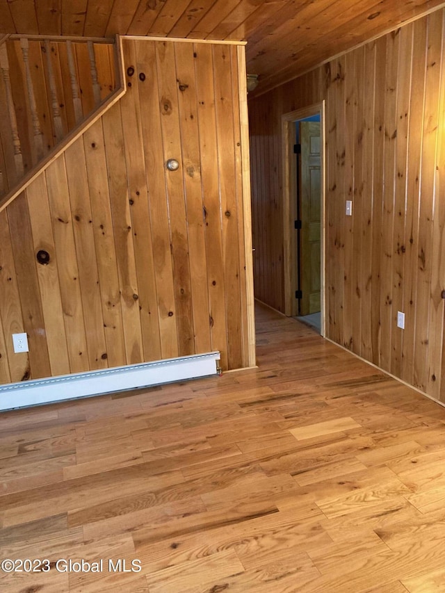 interior space with wooden ceiling, wooden walls, a baseboard radiator, and hardwood / wood-style flooring