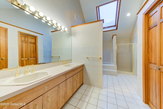 bathroom with tile patterned flooring, vaulted ceiling, vanity, tile walls, and a shower with shower door