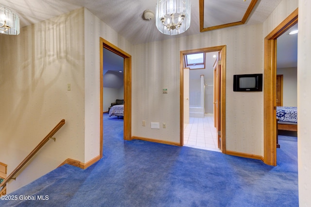 corridor featuring dark carpet and a chandelier