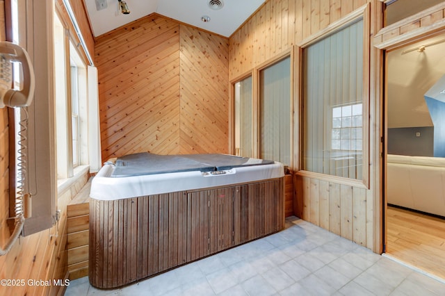 unfurnished bedroom with wooden walls, vaulted ceiling, and multiple windows