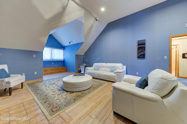 living room with lofted ceiling, track lighting, a textured ceiling, and hardwood / wood-style flooring