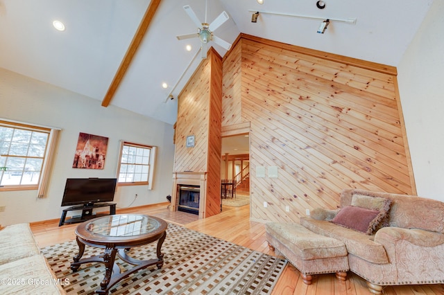 living room featuring high vaulted ceiling, a fireplace, wood walls, and hardwood / wood-style flooring