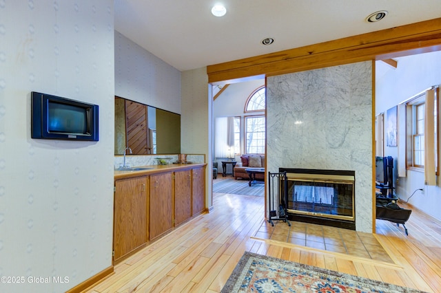 living room with sink, light wood-type flooring, and a large fireplace