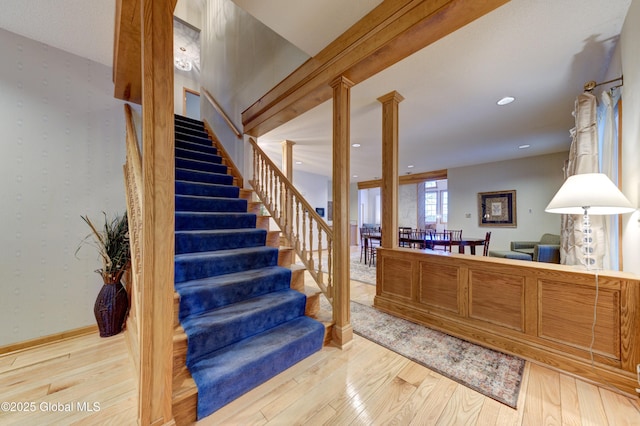 stairs with ornate columns and wood-type flooring