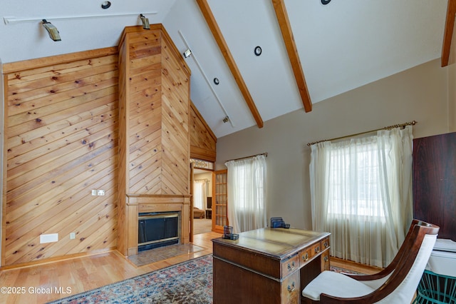 office space with a large fireplace, wood-type flooring, wooden walls, high vaulted ceiling, and beam ceiling