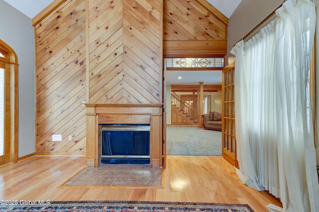 unfurnished living room with high vaulted ceiling, wooden walls, and wood-type flooring