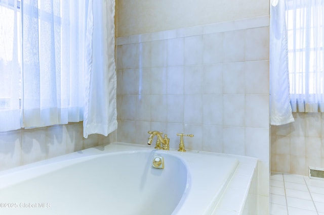 bathroom featuring a healthy amount of sunlight and tiled bath