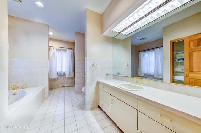 bathroom featuring tile patterned flooring, tile walls, a bathing tub, toilet, and vanity