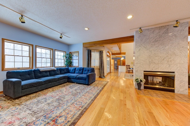 living room with a tile fireplace, a textured ceiling, track lighting, and hardwood / wood-style flooring