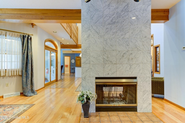 interior space featuring a tiled fireplace, hardwood / wood-style floors, and beam ceiling